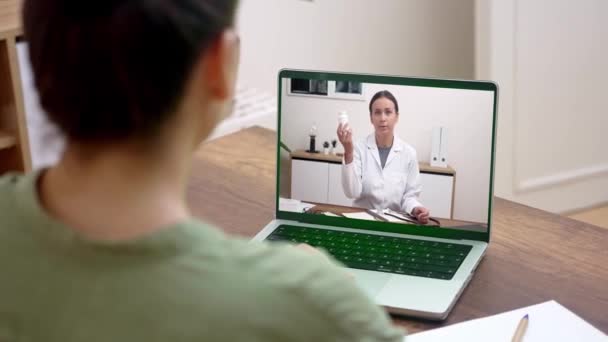 一位病人在家与一名医生通过视频通话 医生正在通过一个安全的远程医疗平台拿着药瓶并提供药物说明 — 图库视频影像