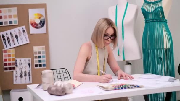 Удумлива Жінка Окулярах Вивчає Ескіз Одягу Столом Моді Ательє Зелена — стокове відео