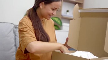 Moda Joy: Kanepesinde, neşeli bir bayan paketini açıyor, başarılı online moda mağazası alışverişi ve ekspres teslimatı ile heyecanlanıyor. 