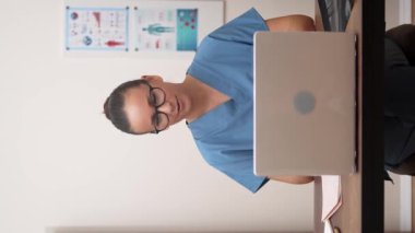 Eylemdeki Teletıp: Bilgisayarına dalmış bir kadın doktor, çevrimiçi tıbbi yardım sağlıyor, video konferansına katılıyor ve tele-sağlık devrimini gösteriyor.