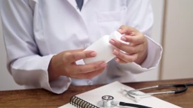 Tıbbi Danışmanlık: Bir eczacı, tedavi seçenekleri ve reçeteleri hakkında düşünmek için elinde bir şişe hap veya vitamin bulunan bir kadın doktora danışmanlık yapar. 