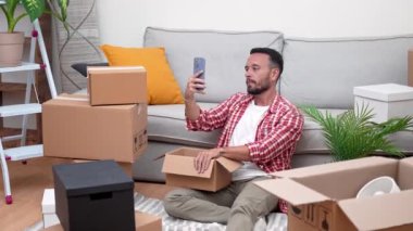 Taşındığı gün kutuları açan genç bir adam video ile bağlantı kuruyor, yeni evinde selfie çekiyor, taşınma ruhunu kucaklıyor.. 