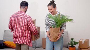 Yurtdışında yerleşmek: Uluslararası bir yere yerleştikten sonra, memnun ve memnun bir çift, yeni oturma odalarında kendilerini evlerinde hisseden bir yığın karton taşınma kutusuyla dururlar..