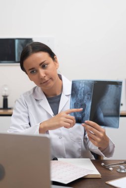 Sanal Danışmanlık: Bir doktor, çevrimiçi tıp ve tele sağlık yoluyla, klinikteki bir görüntülü konuşma sırasında dizüstü bilgisayardaki bir röntgen filmini işaret ediyor. 