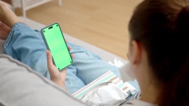 Akıllı telefon kullanan, evden doktorla teletıp danışmanlığında burun peçetesi olan hasta bir kadın.