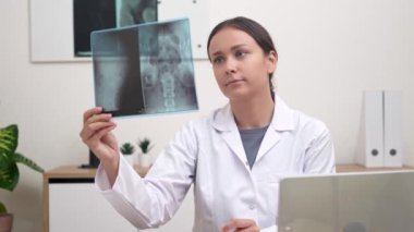 Radyolojik Değerlendirme: Hastanede bir kadın doktor hastanın röntgen filmini titizlikle incelerken, bir radyologsa röntgen sonuçlarını dikkatlice inceler.. 