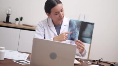 Sanal Tıbbi Tartışma: Bir teletıp videosu sırasında, bir doktor dizüstü bilgisayarında röntgen filmleri sunar ve hastalıkların özelliklerini hastaya açıklar. 
