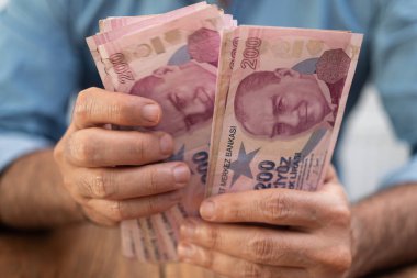 Türk lira banknotlarını elinde tutan erkek turist, döviz kuru prosedürü sonrasında yerel bankada elverişli oranlarda para sayıyor.