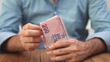 Muhasebeci, müşterilere yatırımlar üzerindeki etkisini hafifletecek mali stratejiler konusunda tavsiyede bulunan enflasyon karmaşıklıklarını gösteren Türk lira banknotlarını dikkatle hesapladı