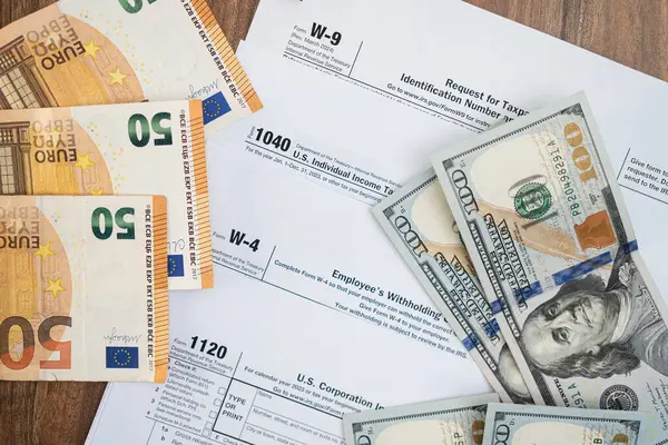 stock image Banknotes of dollar and euro currency placed on different tax forms necessary for taxpayers to report annual income with details in accordance with strict laws on table