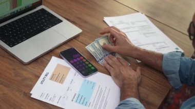 Orta yaşlı muhasebeci masadaki parayı telefon hesap makinesiyle hesaplıyor, gözlüklü adam aylarca bütçeyi düşünüyor ev giderlerini ağır çekimde hesaba katarak.