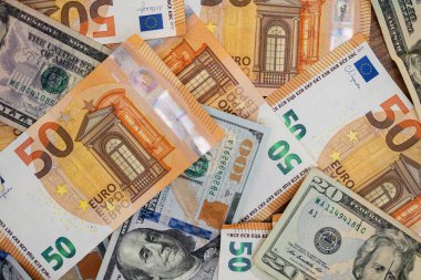 Çeşitli Avro ve Amerikan dolarlarının yakın plan çekimleri bir yüzeye saçıldı. Döviz kurunu, mali işlemleri ve küresel ekonomi kavramlarını temsil eder.