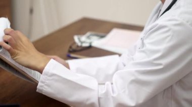 Tıbbi Çalışma Alanı Odak noktası: Bir kavanoz hap, vitamin, ultrason test sonuçları ve ön planda bir eczacının bulunduğu bir doktor çalışma masasının yakın çekimi. 