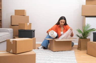 Çekici bir kadın, yeni evde, yeni taşınan mobilyaların bütünlüğünü incelemek için kırsal kesimdeki yeni eve büyük paket kutularını açar.