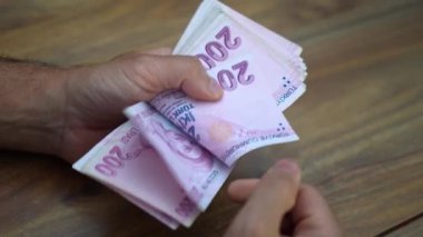 Dükkan sahibi, ülke enflasyonundan derinden etkilenen Türk lira banknotlarını titizlikle saydı ve istikrarlı fiyatlandırmayı sürdürme ve işletme operasyonlarını sürdürme becerisini etkiledi