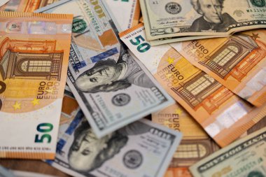 Dağınık Euro ve Amerikan dolarlarının yakın plan çekimi. Uluslararası para birimi değişimi ve küresel finansmanı sembolize ediyor. 