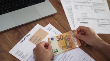 Masadaki 50 avroluk banknotları toplayan beyefendi şirket faturası belgelendirme konseptinin üstündeki parayı dikkatle saydı.