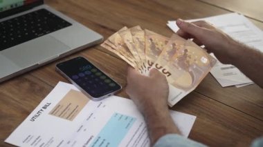 Üst düzey erkek hayranlar, toplam sayıyı sayarak avrodan oluşan banknotlar yığıyor. Eski erkek çalışanlar, ofis masasında ağır çekimde hesaplamalar yaparak çalışıyor.
