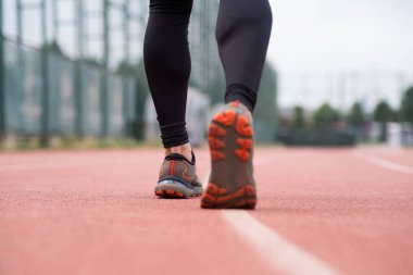 Kendini işine adamış sporcu, şehir tabanındaki kırmızı lastik pistte kararlılıkla koşuyor.. 