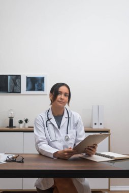 Terapi değerlendirmesi: Son teknoloji ürünü bir klinikte, genç bir kadın terapist masasında çalışırken hastanın test sonuçlarını dikkatlice değerlendirir.. 