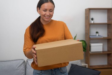 Çok mutlu bir kadın elinde bir karton kutu tutuyor, online satın alma memnuniyetinin somutlaşmış hali.