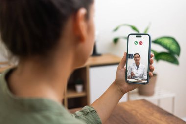 Akıllı bir telefonla gülümseyen bir doktorla görüntülü bir görüşme yapan kişi, tele-sağlık hizmetlerine erişilebilir olduğunu gösteriyor.. 