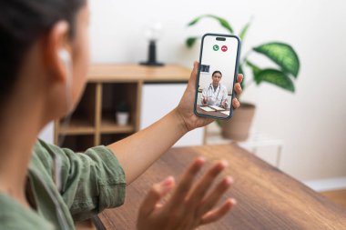 Nişanlanmış bir hasta, bir doktorla akıllı telefondan yapılan video görüşmesi üzerinden hastaların eline odaklanmış bir şekilde ilaç hakkında konuşuyor..