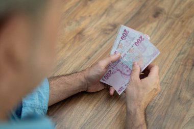 Türk lira banknotlarını elinde tutan erkek şirket muhasebecisi, işyerinde oturan döviz işlemleri için yüksek enflasyonlu para birimini hazırlıyor