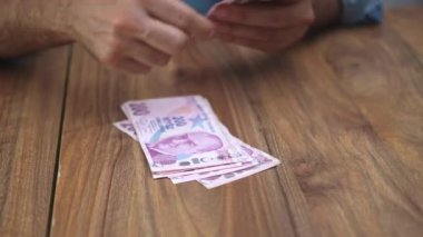 Çalışan, artan yaşam maliyetleriyle başa çıkmak için ek gelir kaynaklarını göz önünde bulundurarak, enflasyonun maaş üzerindeki seyir etkilerinden kaynaklanan Türk lira banknotlarını dikkatle sayıyor