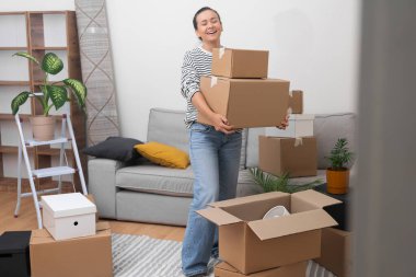 Yeniden yerleştirme Saadeti: Sevinçli ve tatmin olmuş genç bir kadın, yeni evine bir yığın karton taşınma kutusuyla girer ve yeni bir başlangıç yapar..