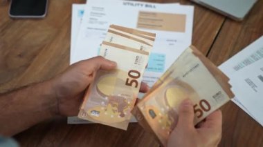 Yaşlı muhasebeci elektrik faturalarının üzerindeki masada avro banknotlarını sayıyor, yaşlı işadamı aylık ev giderlerini yavaş çekimde analiz ediyor