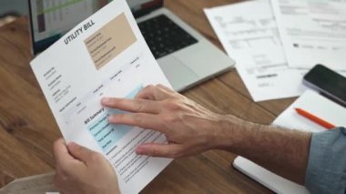 İşadamı dizüstü bilgisayara aktarılan kamu hizmeti faturası hakkındaki ayrıntılı metne işaret ediyor, erkek muhasebeci ev hizmetleriyle ilgili yavaş çekimle ilgili belgeleri inceliyor