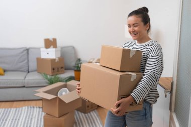 Yeni Yaşam Alanı: Tatmin olmuş genç bir kadın yeni apartman dairesinde duruyor, etrafı karton kutularla çevrili, kendi yerini kendi alanı haline getiriyor.