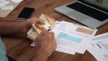 Faturaları takip eden fatura makbuzu masasında oturan erkek muhasebeci avroyu sayarak banknotları açıyor, insan toplam masraf miktarını yavaş çekim hesaplıyor
