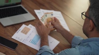 Adam 50 avroluk banknotlara ulaşıyor, her banknotu eliyle sayıyor, işçi elindeki parayı elektrik faturasında belirtildiği gibi ağır çekimde karşılaştırıyor