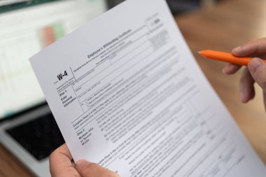 Yeni işe alınan çalışanlar, W-4 formunu doldurmak için modern dizüstü bilgisayardaki verileri karşılaştırarak yeni bir iş için federal vergi beyannamesi dolduruyor.
