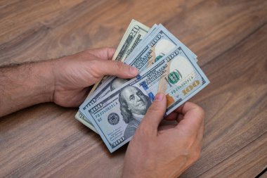 Erkek girişimcilerin elinde çeşitli dolar banknotları mevsimlik maaşlarını ödemek için işyerinde oturan işçilere doğru miktarda para hazırlıyorlar.