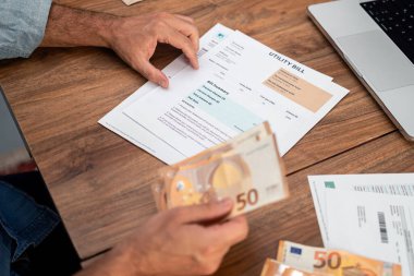 Kıdemli memur elinde euro banknotları tutan faturayı ahşap masa kapanışında okuyor, yaşlı işadamı aylık ev giderleri ve planlama bütçesi için nakit para sayıyor.