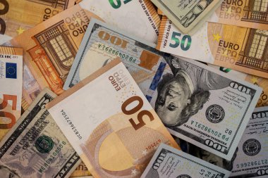 Avro banknotları bulunan dolar banknotları küresel piyasadaki uluslararası ticaret ve yatırım akışlarını etkileyen egemen para birimlerinin istikrarını sembolize ediyor