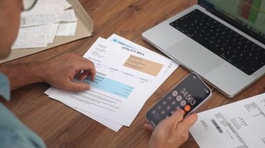 Erkek ofis çalışanı toplam giderleri hesaplayan faturaları denetliyor, muhasebeci ev harcamaları hakkında telefon hesap makinası yavaş çekim ile rapor hazırlıyor