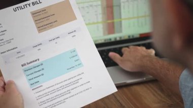 Orta yaşlı beyefendi verileri bilgisayara aktaran fatura detaylarını inceliyor, erkek muhasebeci ofis faturası özetlerini yavaş çekimde gözden geçiriyor.