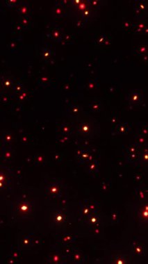 Siyah uzayda yüzen parlak kırmızı-turuncu kıvılcımlar, ateşi, enerjiyi veya kutlamaları görselleştirmek için sinematik dikey parçacık animasyonu, 4K biçimi