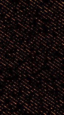 Siyah arka planda parlayan turuncu çizgilerin çapraz akışı. Dijital desenler, veri akışı veya hareket tasarımı için soyut dikey 4K animasyonu.