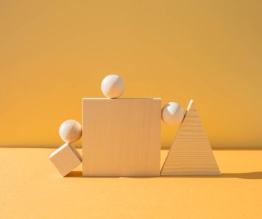 Sarı arka planda birkaç ahşap figür, sert ışık. Denge kavramı.