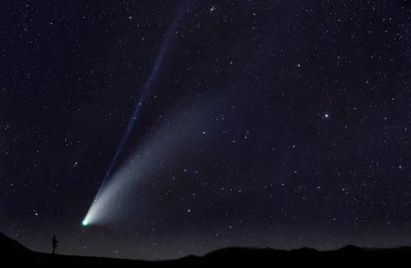 Silhouette Des Menschen Beim Fotografieren Des Kometen Der Zwischen Sternen Stockbild