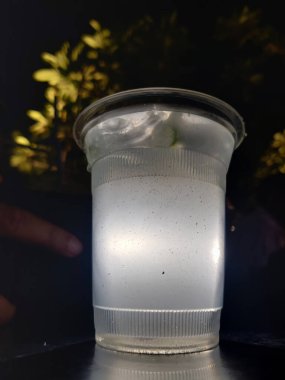 Buzlu kola. Bardakta buz küpleri ve açık havada samanla çekilmiş taze soğuk bir içecek.