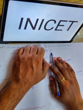 Sınava hazırlanan bir kitabı okuyan bir kişinin resmi. INICET ön taraftaki bir ekranda yazılır. INICET, Hindistan 'da tıbbi giriş sınavıdır.