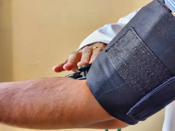 Doktorun beyaz önlük giyip hastanın tansiyonunu ölçerken fotoğrafı.
