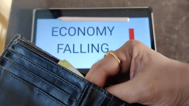 財布からお金を出している人の映像 下向きの矢印で落下経済は背景に書かれています 映像は経済の秋を描いた — ストック動画