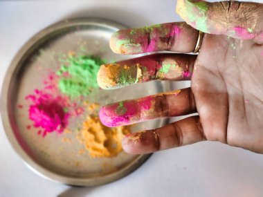Arka planda Holi renk plakası ile elde çekilen renkli holi tozu resmi. Hindistan 'da Holi festivali